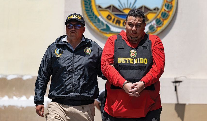 Un policía peruano traslada a uno de los integrantes de la organización criminal Tren de Aragua, en Lima, Perú.