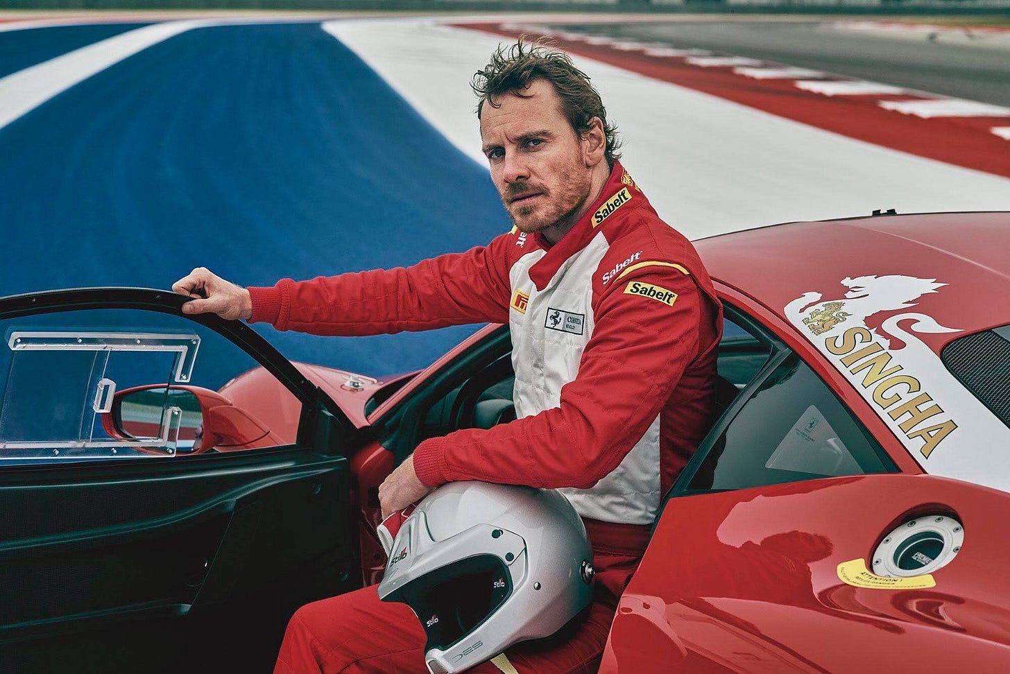 michael fassbender sitting in red race car