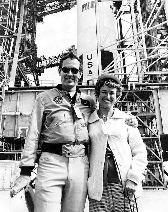 A black and white photograph of a young man and women in 1970’s dress in front of a rocket.