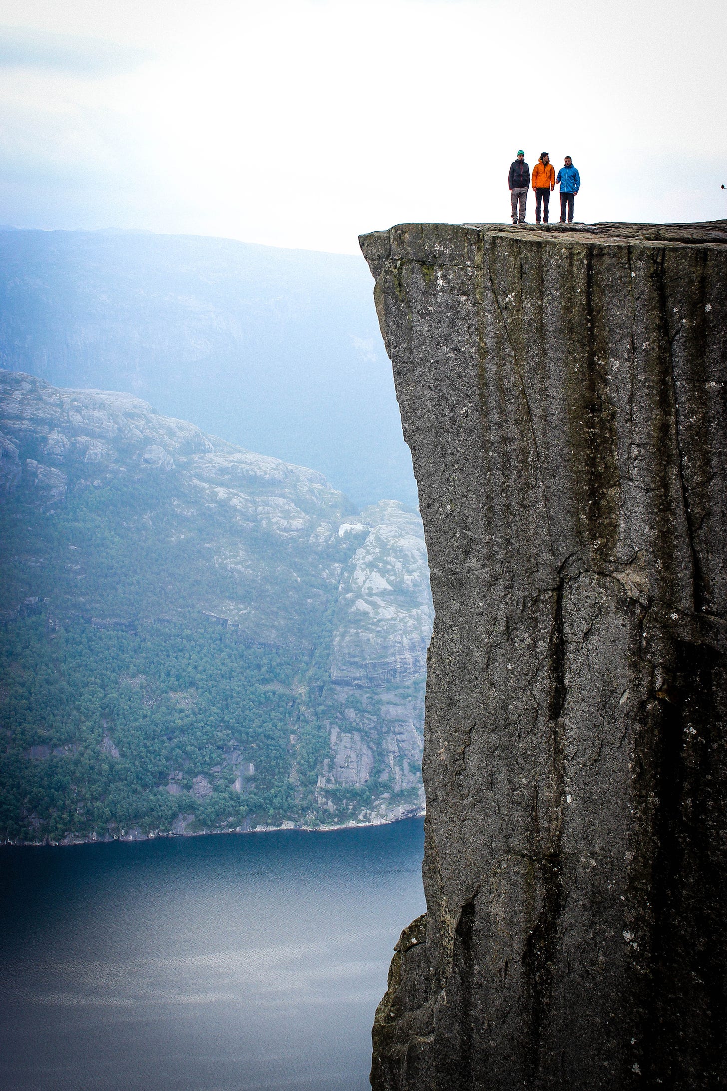 three people standing on a precipice