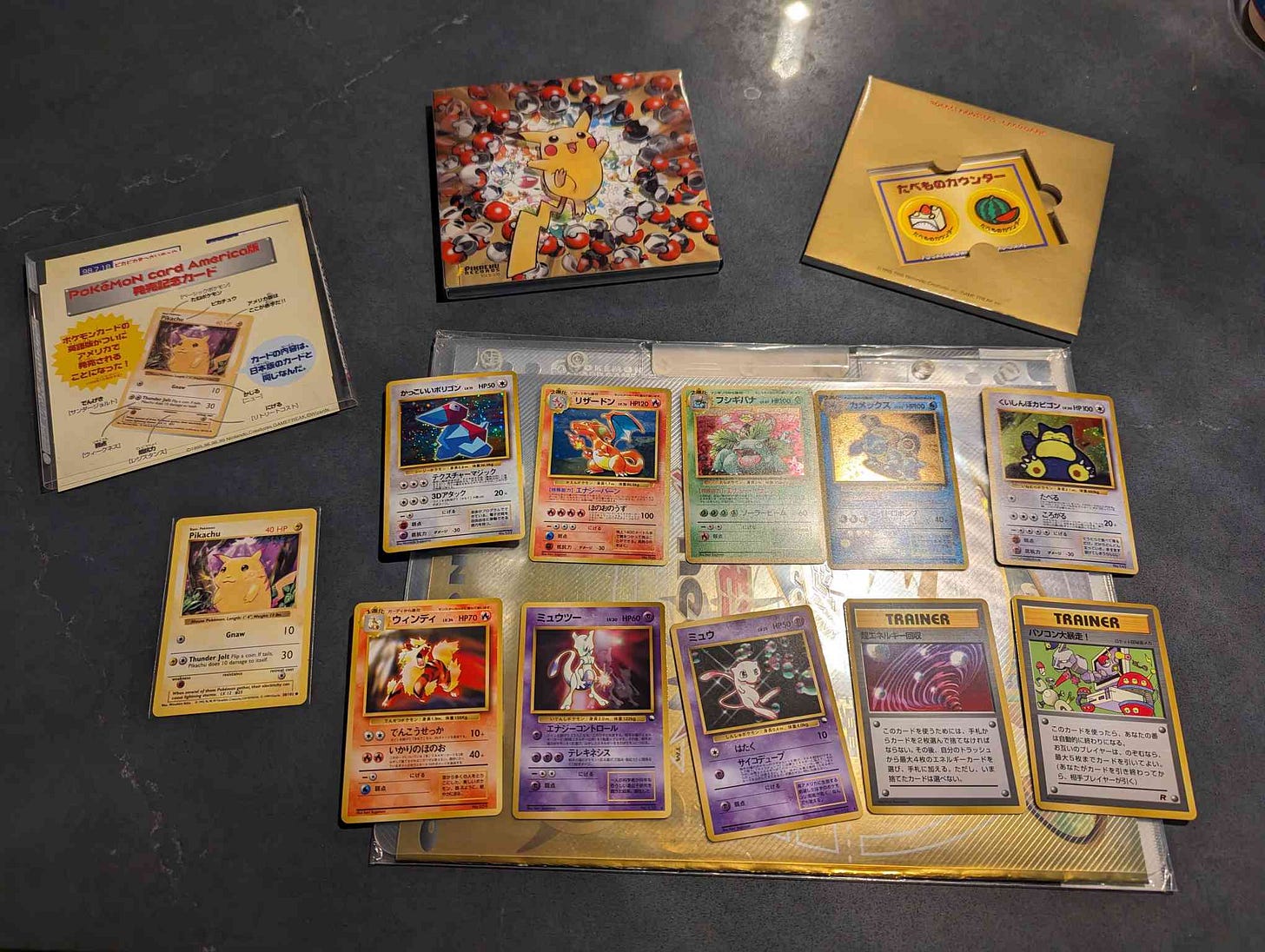 A photograph showing the inside of Jaxel's Pokémon Song Best Collection CD, showing a large selction of Japanese promo cards, and an English Base Set Pikachu.