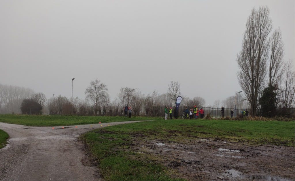 View of the finish line from the course, with the parkrun 'feather' flag flying above it and volunteers waiting for finishers.