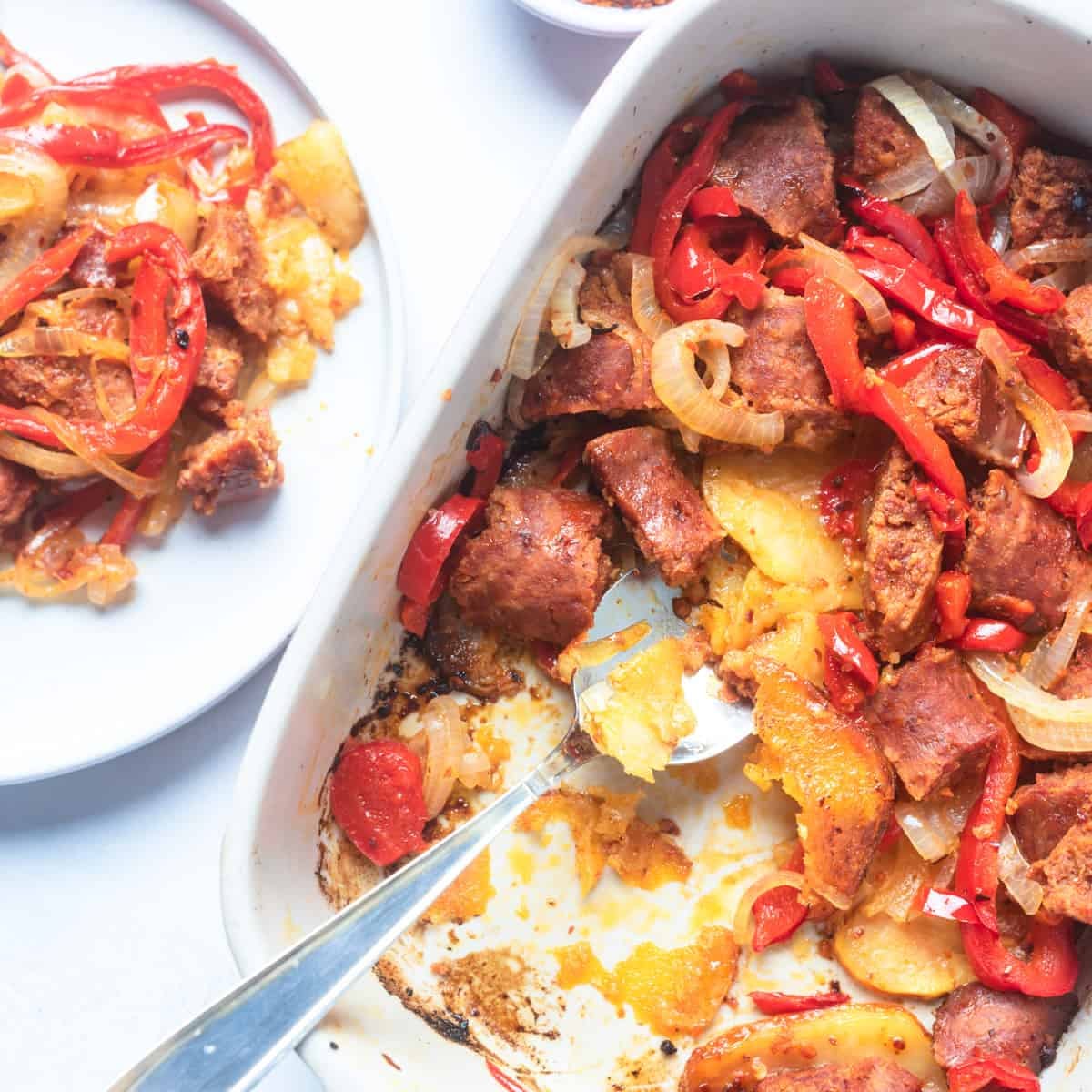 Potato and sausage casserole with serving spoon in a baking dish.