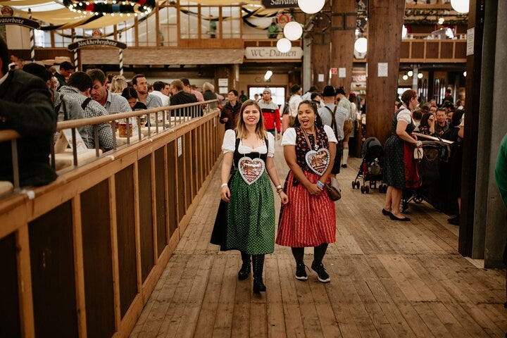 Friends in Bavarian dress enjoy a beer hall at KBYG Oktoberfest in Munich.