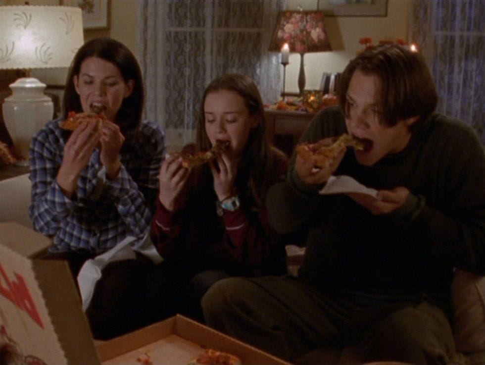 Lorelai, Rory, and Dean are biting into slices of pizza with everything on them. 