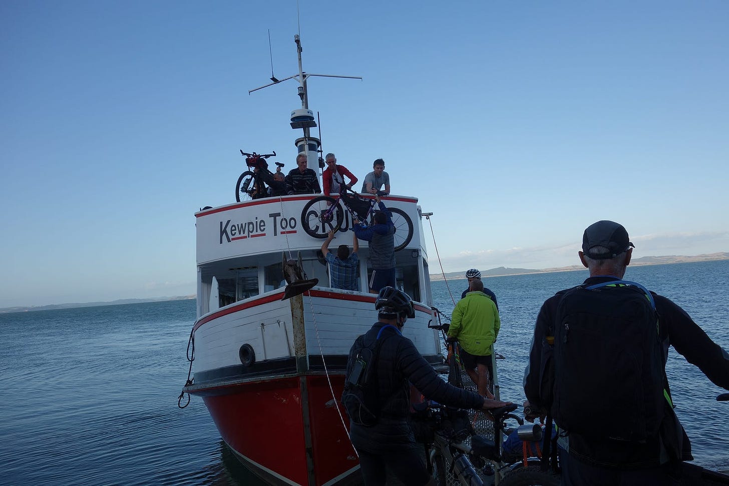 Bikepackers lifting bicycles onto a small ferry.