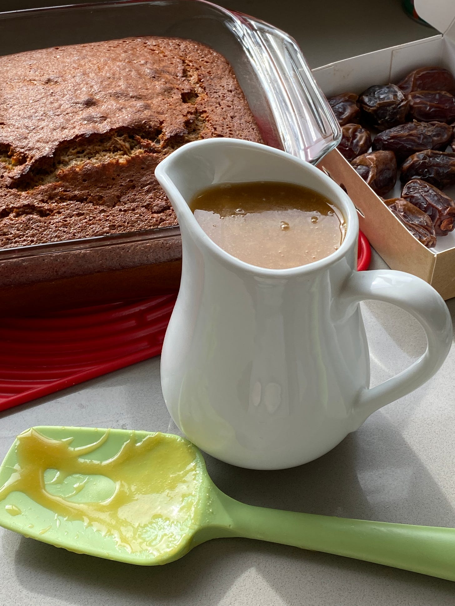 Toffee Sauce in a white jug, with toffee pudding and sauce in a white serving dish. 