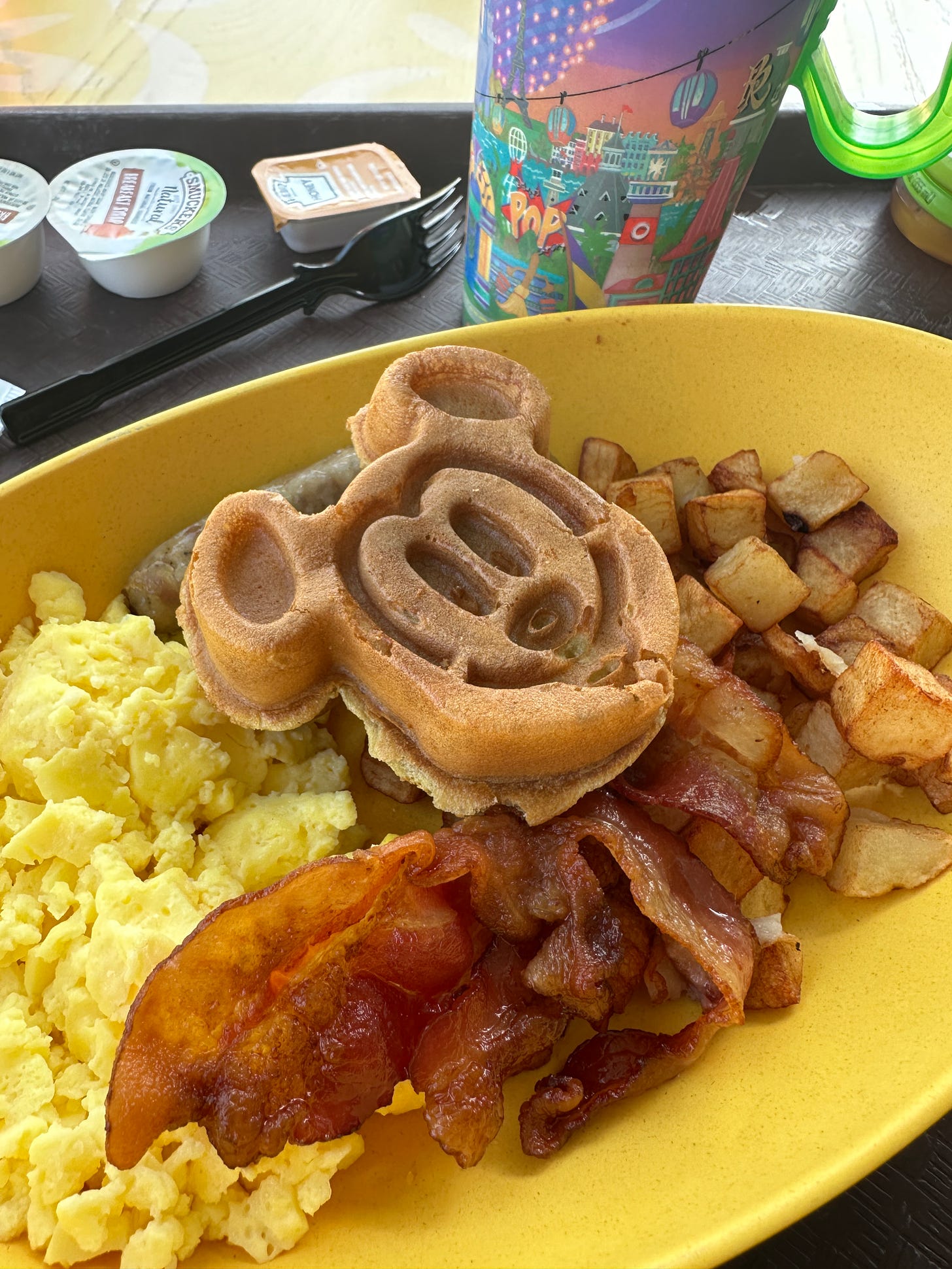 A Mickey waffle and other breakfast items on a tray