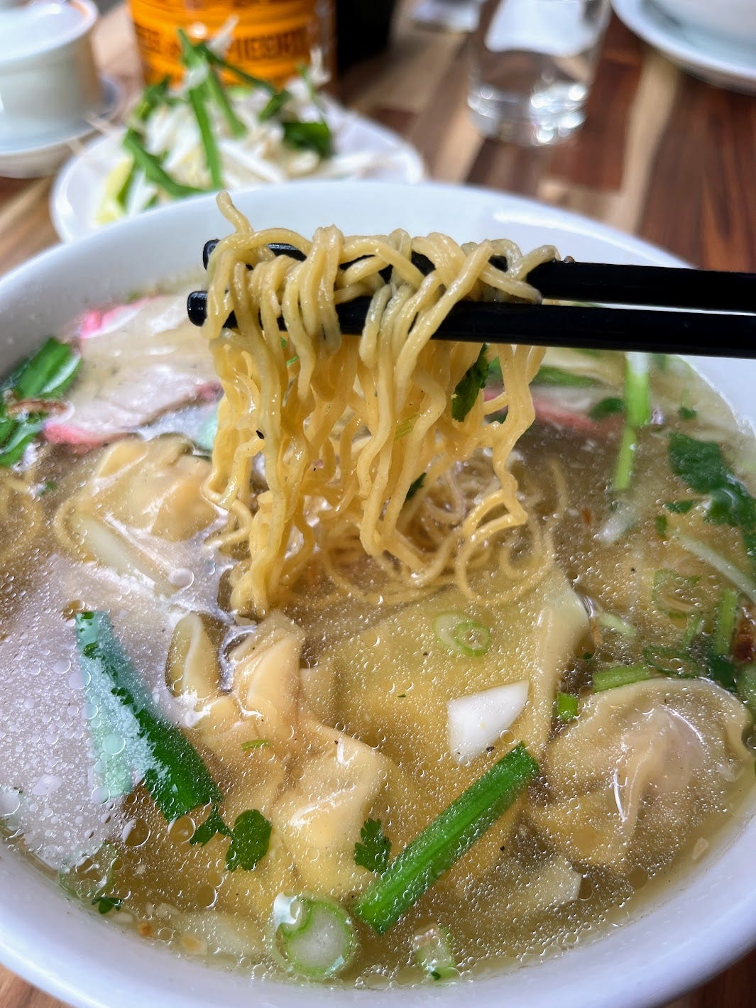 Mì hoành thánh with chopsticks holding up noodles