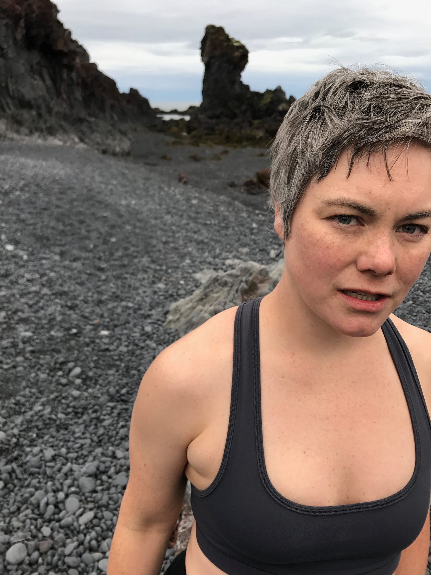 A photograph of the author with a pained expression. She is wearing a dark gray sports bra, is sweaty, and does not have a defined musculature.