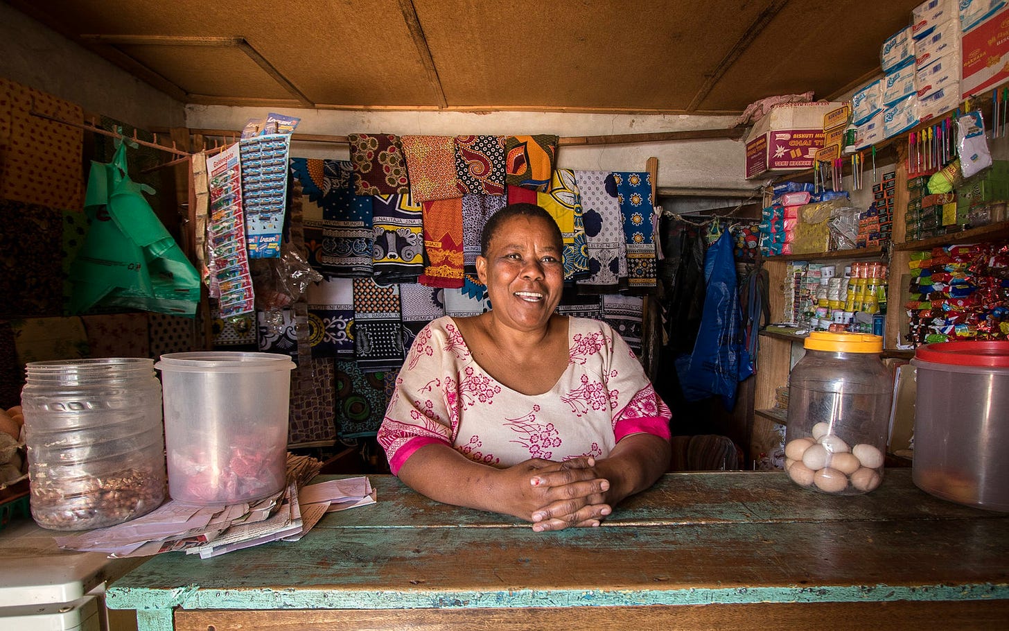 African woman smiling behind the counter of her small shop.