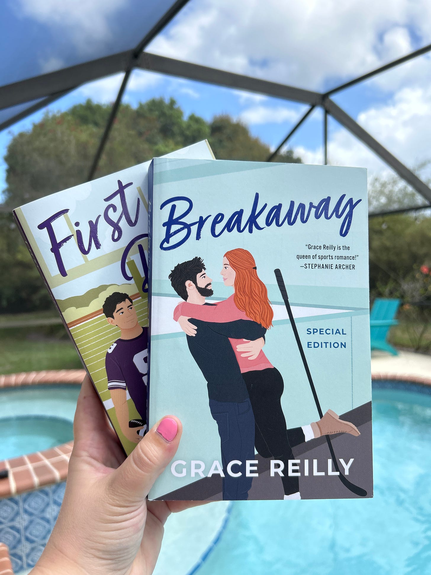 A picture of First Down and Breakaway by Grace Reilly from Avon books, in front of an outdoor pool