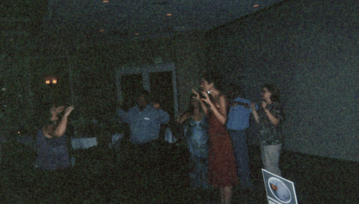 people holding their arms up dancing in a dark room