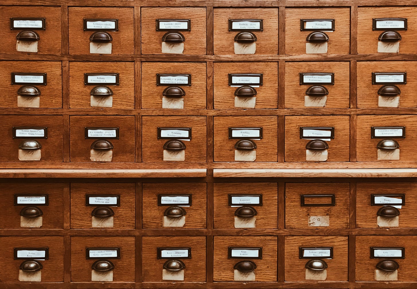 Old fashioned pull out file drawers with labels. Photo by Jan Antonin Kolar on Unsplash
