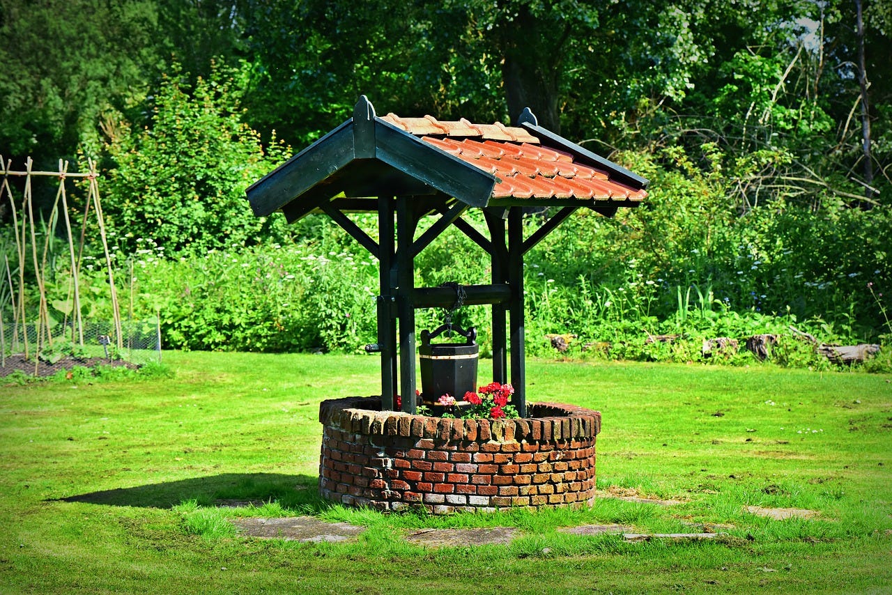 A red-brick well in the middle of a green lawn