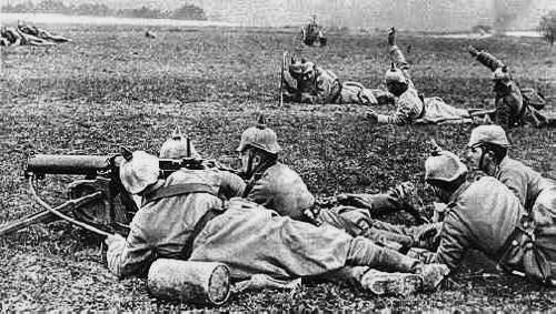 Black and white photo of a German machine gun crew using an MG08 machine gun in a open field. It looks like a training exercise from early in the war.