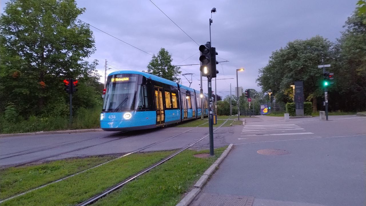 A street with a modern lightrail and green spaces