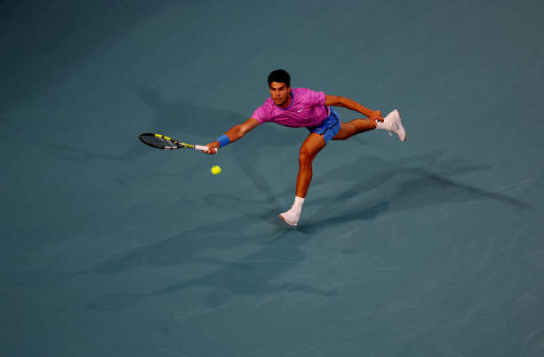 Carlos Alcaraz of Spain returns a shot against Grigor Dimitrov of Bulgaria during their match on Day 13 of the Miami Open at Hard Rock Stadium on...