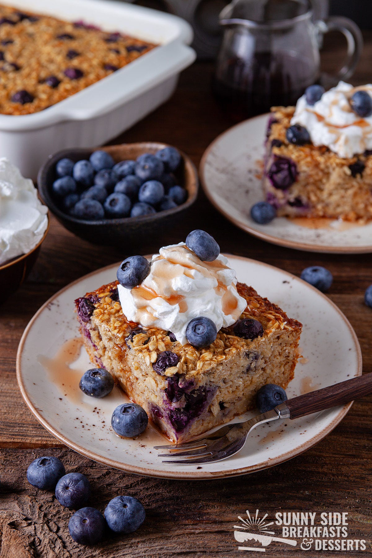 Slice of blueberry baked oatmeal with whipped cream and syrup.