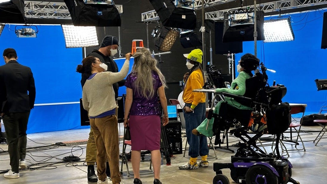 An on-set photo of The Squeaky Wheel's crew members. All of whom wear protective face masks as they prepare to shoot a scene. An on-set photo of The Squeaky Wheel's crew members. All of whom wear protective face masks as they prepare to shoot a scene.