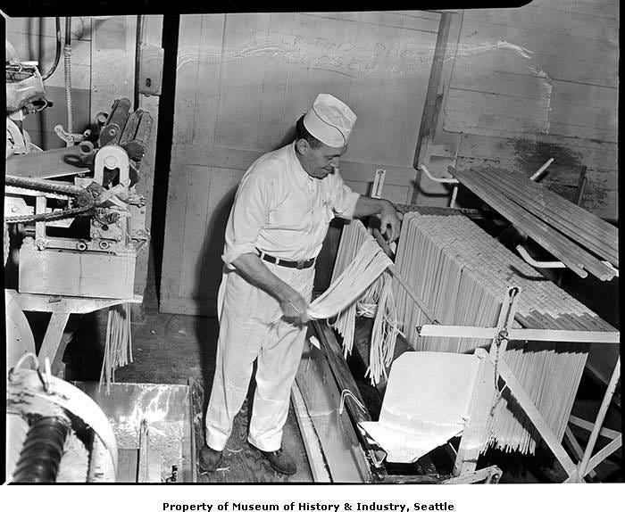 Man hanging noodles on a drying rack at the Mission Macaroni Company, Seattle, January 1952