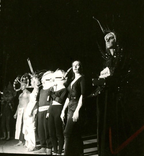 Seven individuals in costumes pictured in black and white image