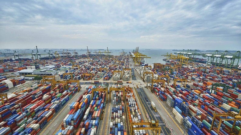An aerial photo from the Port of Singapore, showing shipping containers lined up on the dock in rows and sea in the distance.