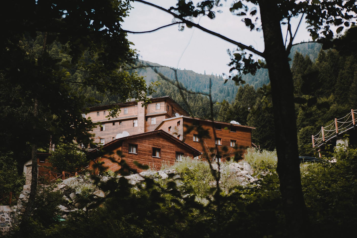 a photo of a large complex of cabins hidden deep in the mountain forest.
