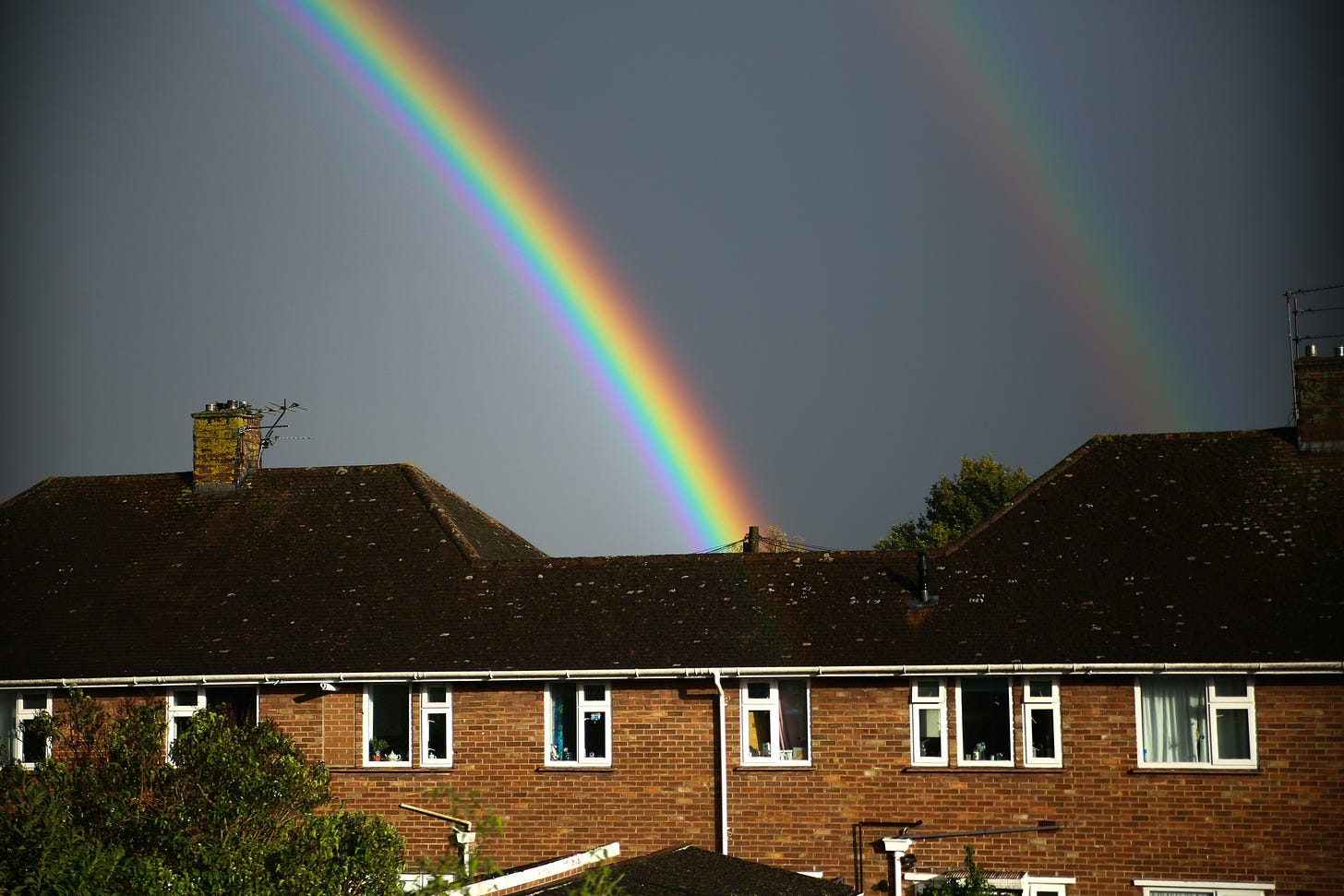 A rainbow over a brick house. 