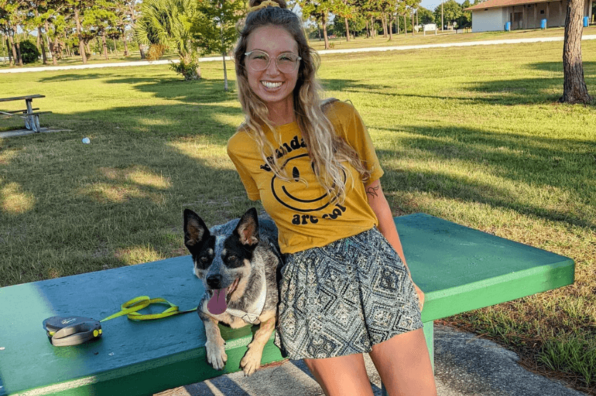 Haley the human and Scout the blue heeler pose on a picnic table at a park