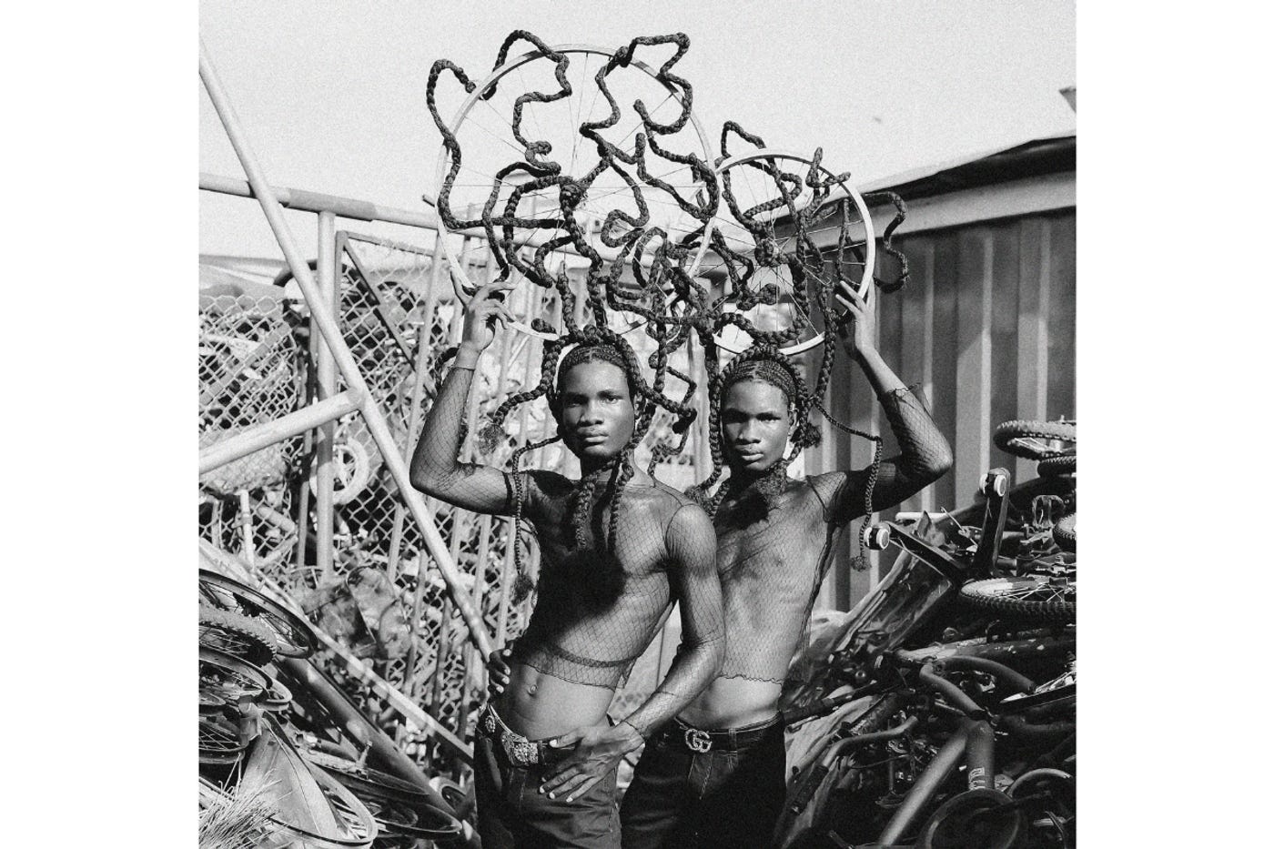 A photo showing two models with headpieces made from bicycle tire rims that have braids from their hair entangled in them.