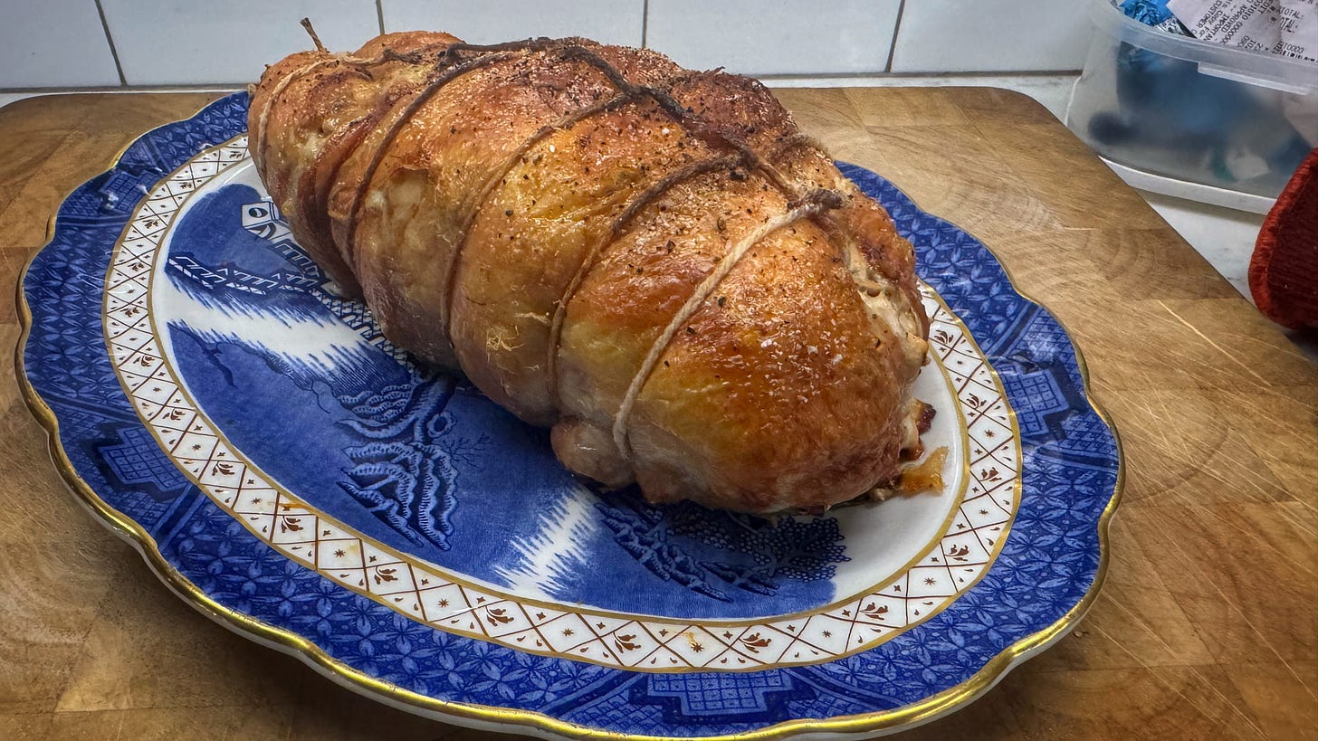 A platter holding a trussed and fully cooked and browned chicken ballotine
