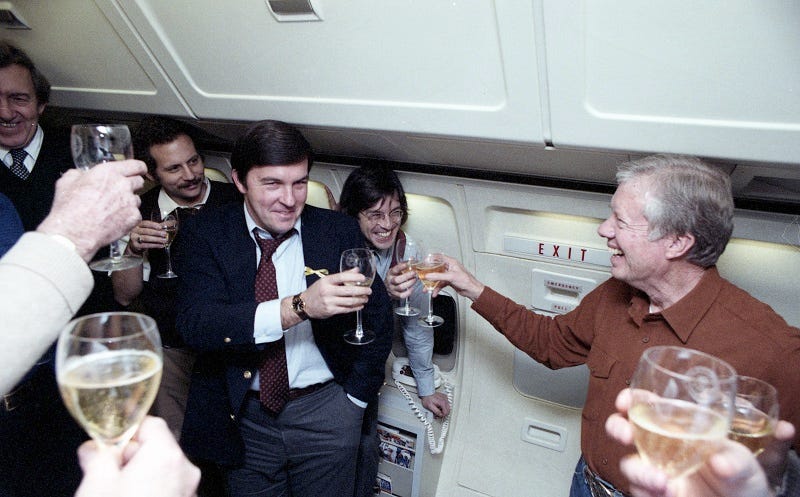 Edmund Muskie, Hamilton Jordan, Rick Hertzberg, President Carter, and others drink champagne out of glass goblet on "Special Air Mission" 26000, after the #IranHostageRelease. It's a closeup so only a few people are in it. They're very happy. 