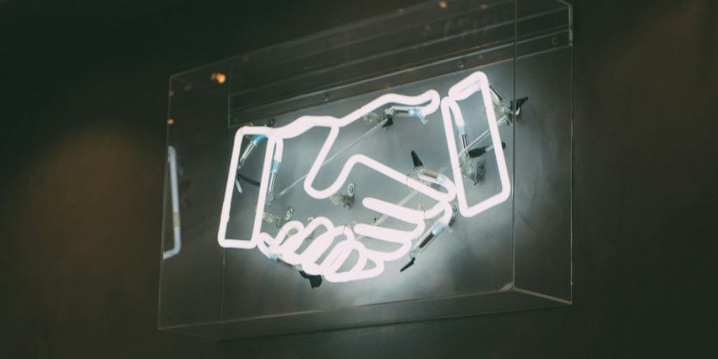 Neon sign in shape of handshake white against black