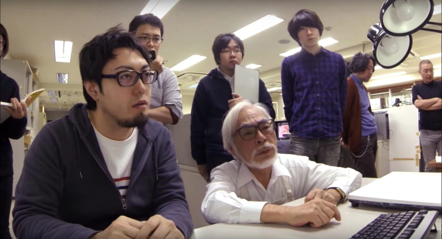 Hayao Miyazaki sitting with a team of animators.