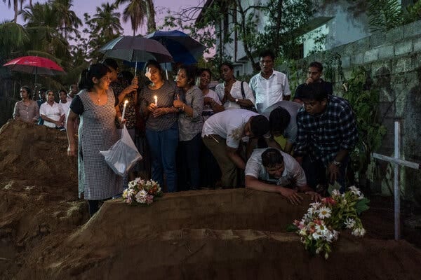 Relatives lighting candles after the burial of three victims of the same family who died in the bombing at St. Sebastian Church in Negombo, Sri Lanka, in 2019.