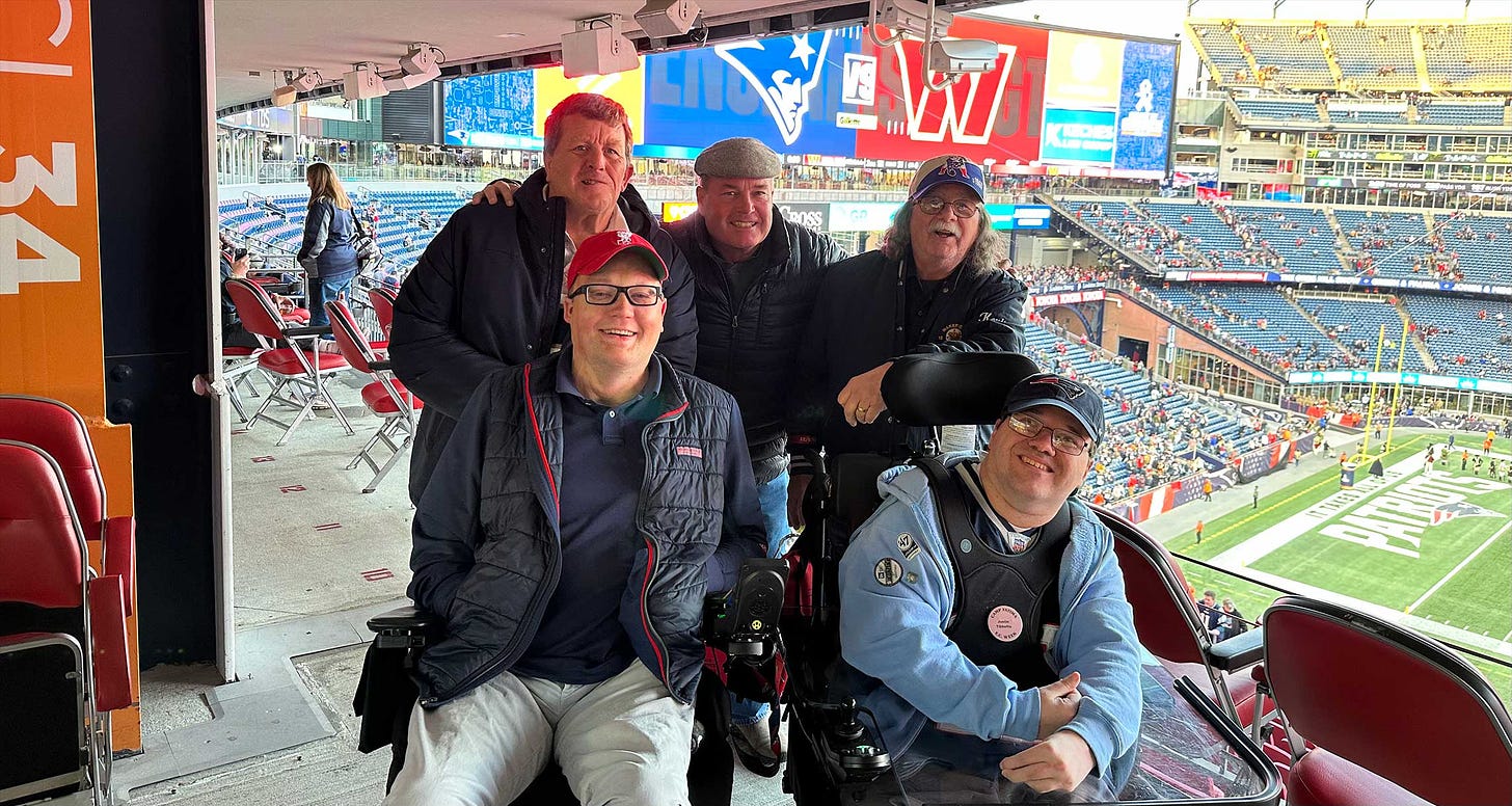 John with four new friends at the football game, one of whom is also a wheelchair user.