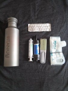 Inside the pouch, left to right: filter cleaning syringe, Sawyer Mini, and Steripen Freedom