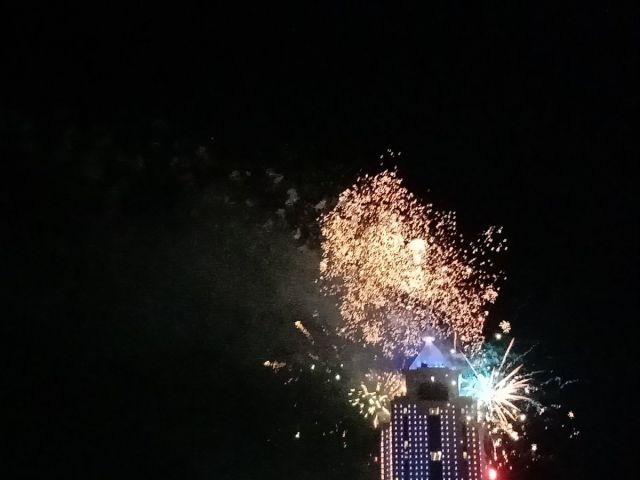 A skyscraper with fireworks exploding behind it