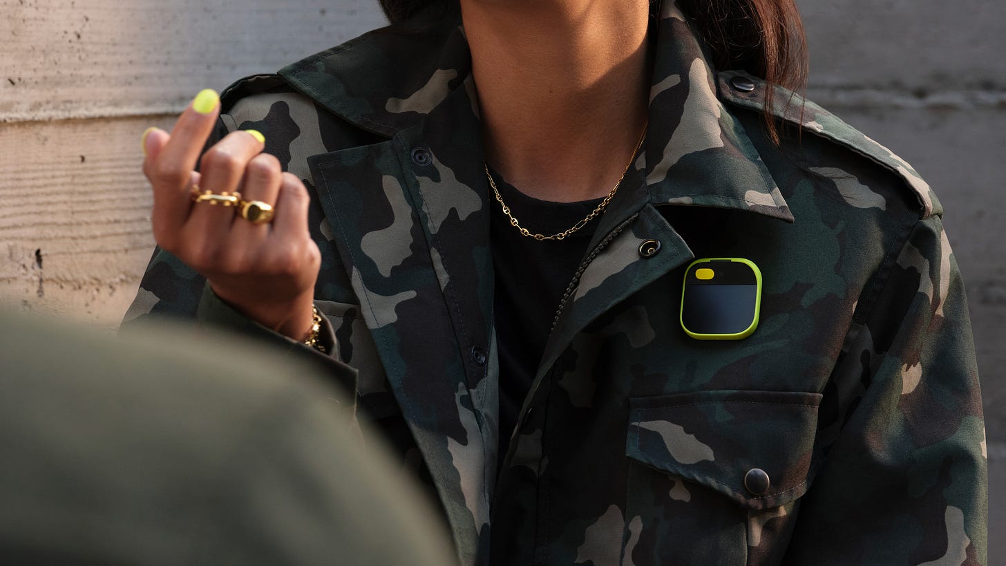 A Humane AI pin shown being worn by a woman clipped to a military jacket (Humane)