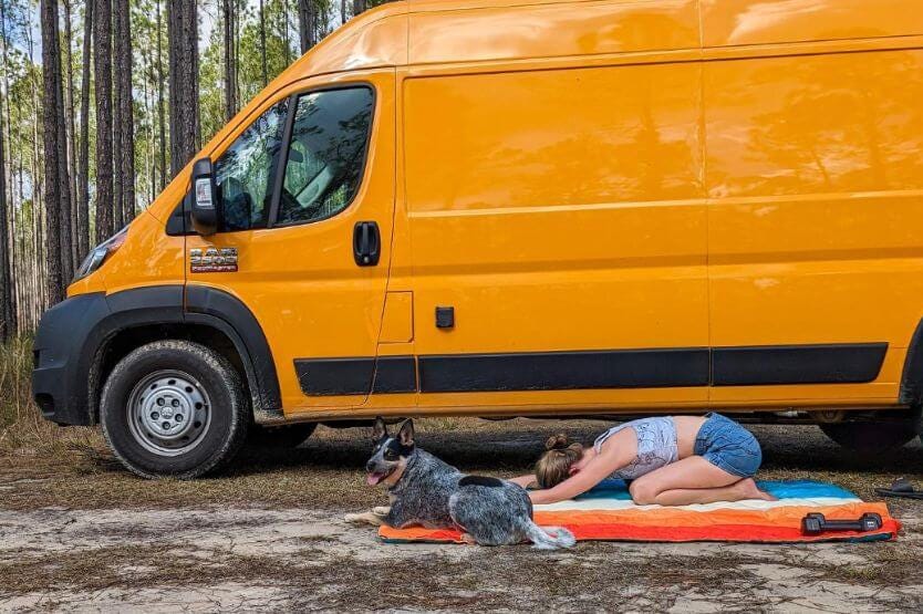 Haley and Scout stretch on a rainbow colored Rumpl blanket in front of our bright yellow converted camper van