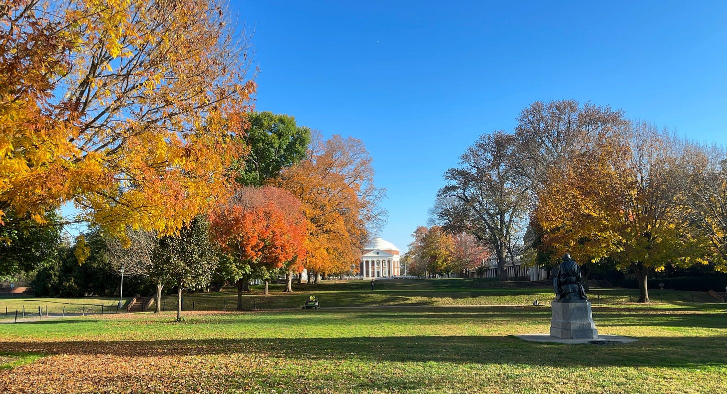 Green grass. Fall foliage. Homer statue. Rotunda visible in distance. Bright clear blue sky.
