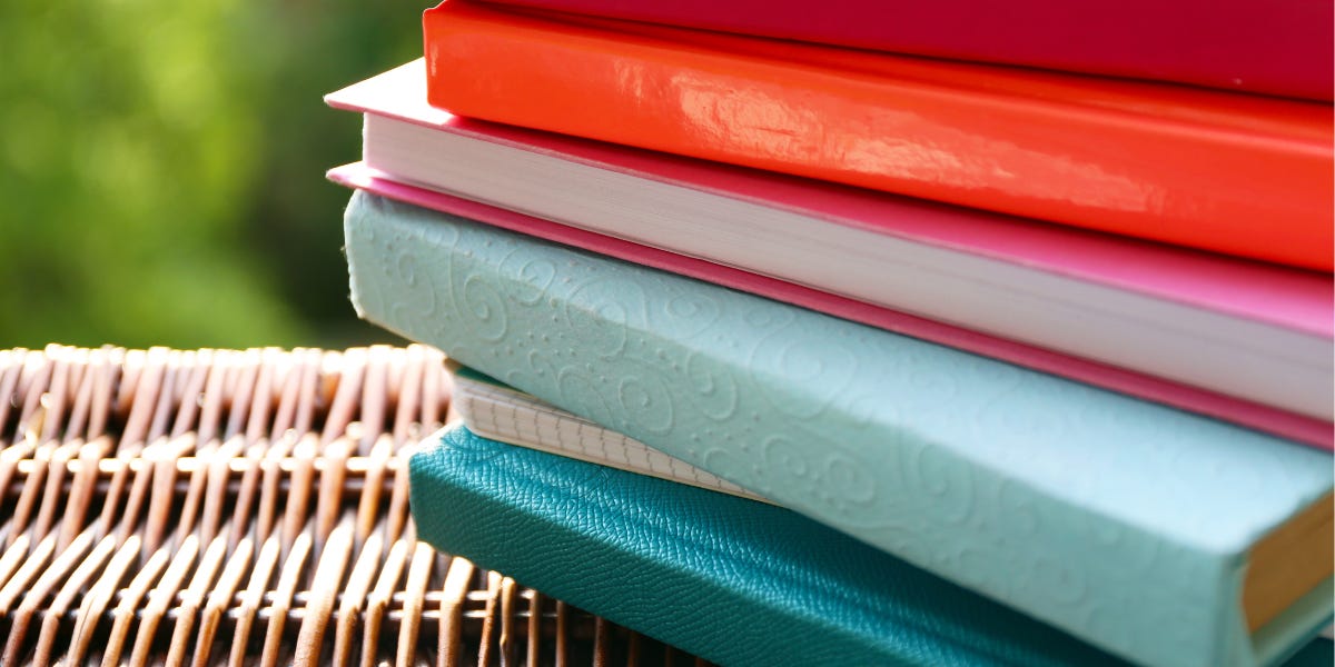 a small stack of planners in various colors and textures