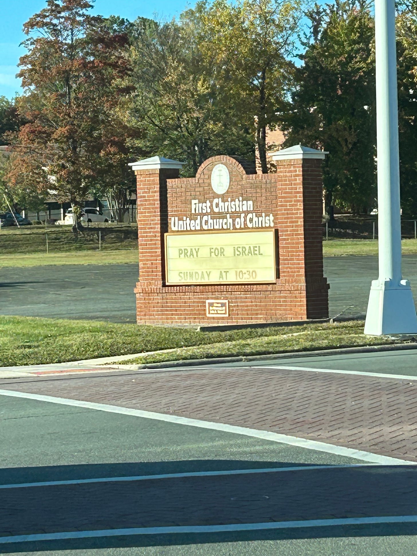 A brick church sign with "Pray for Israel. Sunday at 10:30."