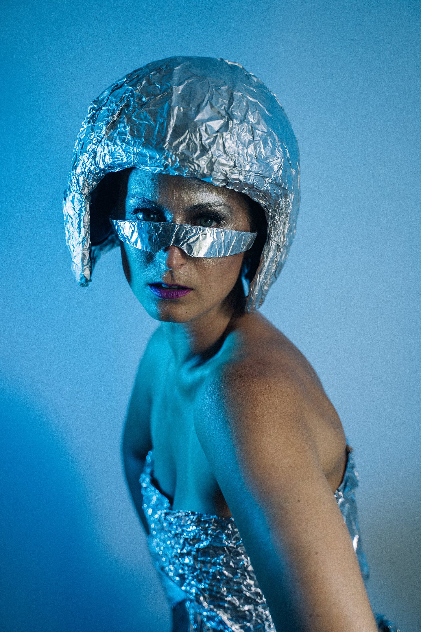 A white woman in a helmet, dress, and sunglasses made of tinfoil. Extremely space.