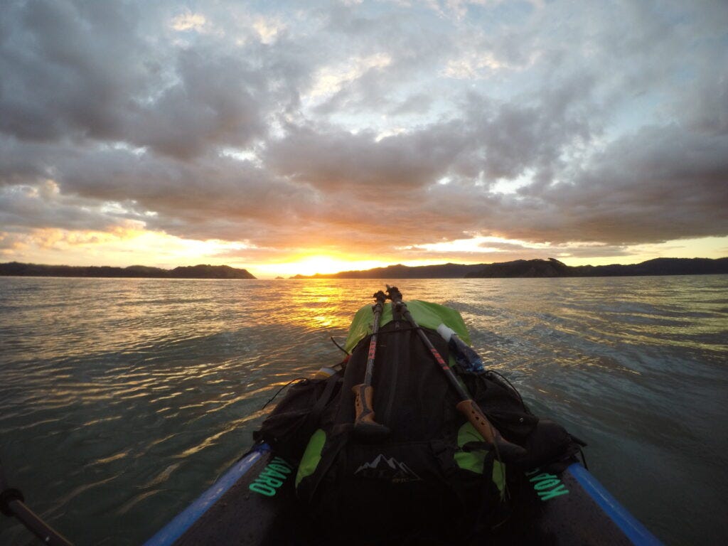 Raft facing out to the Tasman Sea as the sun sets behind the islands of Whatipū Beach