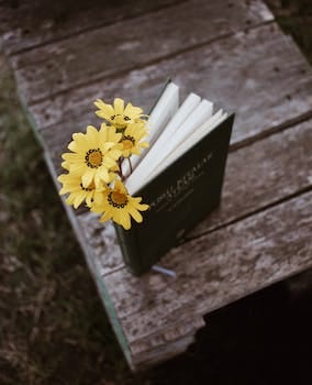 blooming gazania bouquet between book pages on wooden planks