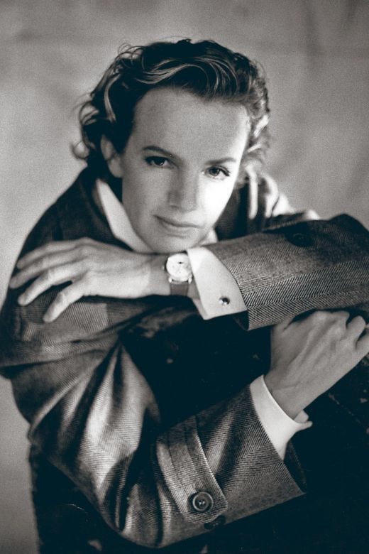 A fair-skinned woman with dark blonde hair sits for a portait wearing a suit, dress shirt and watch while staring directly into the camera lens.