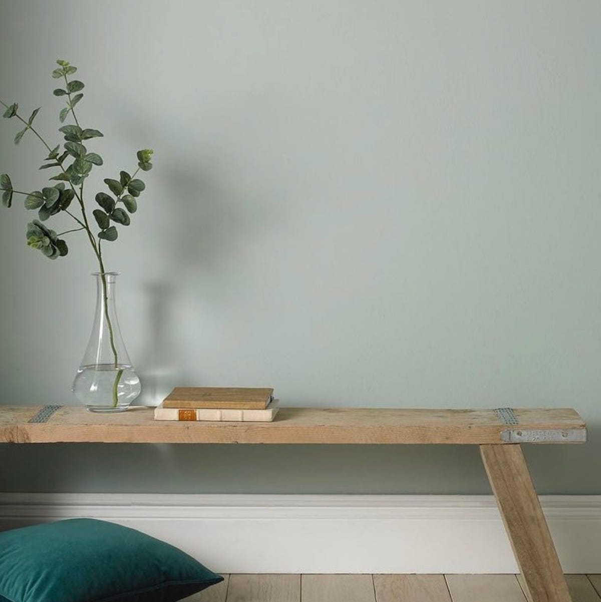 a calm tone of green painted on a wall with a wooden bench positioned in front