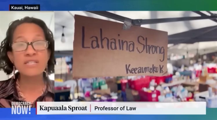 Law professor Kapuaʻala Sproat speaking next to image of big sign in an emergency shelter that reads "Lahaina Strong"